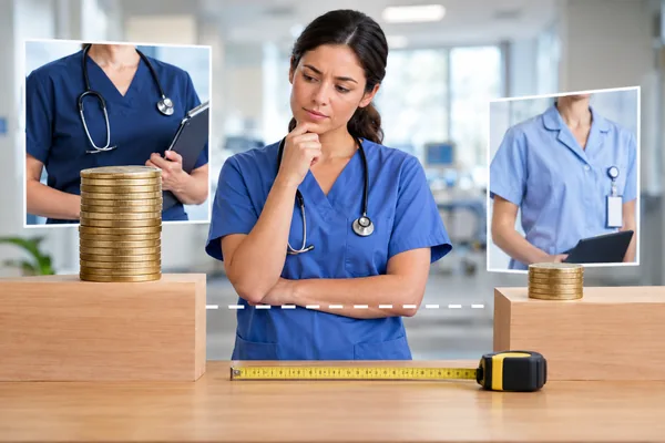 A nurse in blue scrubs with a stethoscope standing between two raised wooden blocks holding stacks of coins, a dashed line between them and a tape measure in front
