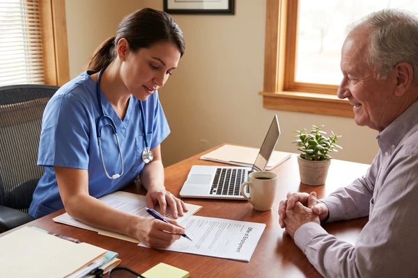 A nurse in scrubs reading a printed Offer of Employment form with a practice manager across a desk, pen in hand.